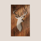 A deer head silhouette wall art piece cutout, set against a rustic brown wood plank background, centered on a solid light beige backdrop.